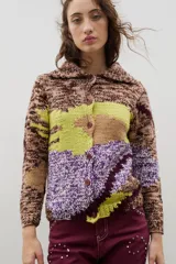 Saco de punto con diseño de bloques de color en técnica intarsia, combinando tonos marrones jaspeados, verde lima y violeta. Presenta cuello redondo, cierre frontal con botones y mangas largas.