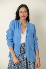 Blazer celeste de lino con corte recto, cuello mao y aplique desflecado en cuello y ruedo.