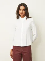 Camisa de manga larga color blanco, con cuello alto tipo mao con detalle de volados y cierre frontal de botones.