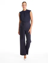 Enterito de crepe color azul marino, con torso plisado sin mangas y cuello alto. Presenta corte en la cintura con lazo de ajuste y pantalón de pierna recta con bolsillos funcionales.