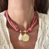 Gargantilla con cordón doble en tonos naranja y gris, con dije de concha dorada y dije de caracol blanco.