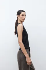 Top sin mangas color verde oliva, con cuello redondo y detalle de ojalillos metálicos a lo largo de los hombros.