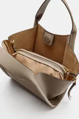 Bolso bandolera de formato city en color gris topo, con pespuntes decorativos, doble asa de mano, cremalleras laterales y cierre imantado.