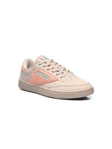 Championes Umbro modelo Rian, de diseño clásico en color blanco con detalles en rosado en el talón y logo lateral. Presentan suela de goma en tono crema y perforaciones en la puntera para mayor ventilación.