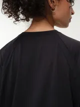 Remera deportiva de color rosado con diseño oversized y mangas raglán cortas, confeccionada en tela dry fit. Cuenta con cuello redondo clásico y detalle de etiqueta en el lateral inferior.