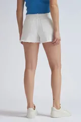 Short de jean corto color blanco crudo, de tiro alto y diseño ajustado, con dobladillo deshilachado y aberturas laterales en las piernas.