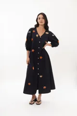 Vestido midi negro de algodón con escote en V, mangas 3/4 abullonadas y abotonadura frontal. Presenta bordados de motivos marinos en tonos naranja y blanco.