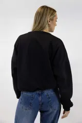 Buzo negro de cuello redondo y mangas largas, con estampa frontal en color blanco con la leyenda "DREAM BIG Start Small" y detalles de texto.