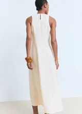 Vestido midi evasé color crudo, sin mangas, con cuello caja y cierre posterior de cremallera y botón.