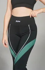 Calza deportiva larga negra con franja verde y línea blanca en los laterales.