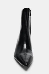 Botín de tacón kitten en acabado charol negro, con diseño de punta fina y cierre lateral mediante cremallera.