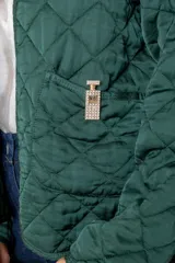 Campera corta de diseño capitoneado con patrón de rombos, color negro. Presenta cuello redondo, cierre frontal abierto, mangas largas y dos bolsillos delanteros con detalle de broche.