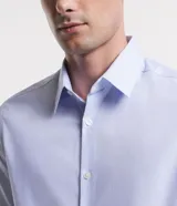 Camisa de manga larga con cuello inglés y cierre frontal abotonado. Confeccionada en tejido tricolina maquinetado con patrón de rayas finas, destacando por su alta transpirabilidad y suavidad.