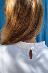 Remera de manga larga color blanco, confeccionada en algodón, con detalle de volados en los puños.