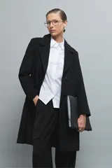 Camisa blanca de manga larga con cuello clásico y cierre frontal con botones. Presenta dos bolsillos plaqué en el pecho.