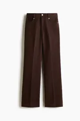 Pantalón bootcut de sarga de algodón, color marrón, con cintura clásica, cierre con botón y bolsillos delanteros. Presenta pliegues marcados al frente y en la parte trasera.