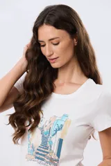 Remera blanca de manga corta y cuello redondo, con estampa frontal ilustrativa de un paisaje urbano con escalinatas en tonos azules y tierra.