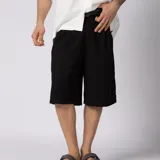 Bermuda sastrera gris de corte baggy, con pinzas al frente y diseño holgado que se extiende por debajo de la rodilla.