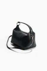 Cartera negra de cuero sintético con textura granulada, diseño rectangular, cierre superior y anillas decorativas metálicas. Incluye asa corta de mano y correa fina ajustable y extraíble para usar cruzada o al hombro.
