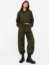 Pantalon estilo parachute verde militar con cintura elastizada ajustable mediante cordón, bolsillos laterales y puños ajustables en los tobillos.
