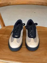 Championes urbanos de cuero con diseño de paneles en tonos beige y marrón, con cordones negros y suela de goma negra.