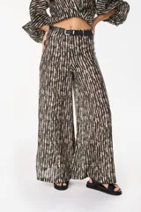 Pantalón de lino italiano con diseño estampado a rayas verticales en tonos negro y beige, de tiro medio y corte ancho.