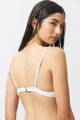 Top de bikini blanco con escote halter, abertura circular en el centro y lazos ajustables.