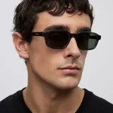 Lentes de sol con montura rectangular de diseño contemporáneo en color gris translúcido y cristales en tono verde oscuro.