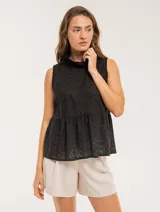 Blusa blanca sin mangas, con cuello alto con volados y detalles bordados con motivos florales.