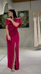 Vestido largo de fiesta color magenta, con escote estilo bardot que deja los hombros al descubierto, ajuste entallado en la cintura y falda con tajo frontal profundo.