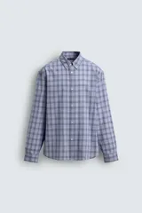 Camisa de corte relajado confeccionada en tejido de algodón, con estampado de cuadros en tonos azules. Presenta cuello abotonado, manga larga con puños abotonados y cierre frontal con botones.