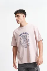 Remera color rosa claro de corte oversize con cuello redondo y mangas cortas. Estampado frontal con un tigre, estrellas y texto "Jungle Army".