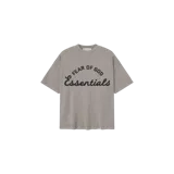 Remera oversize gris topo con estampado frontal que combina texto en tipografía sans-serif ("FEAR OF GOD") y cursiva ("Essentials") en color negro.