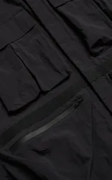 Chaqueta técnica liviana de microfibra con acabado mate, diseño con mangas desmontables que permiten convertirla en chaleco. Cuenta con cuello tipo camisa, cierre frontal oculto, cuatro bolsillos frontales de gran tamaño y puños elásticos. Incluye logo bordado en relieve en el pecho.