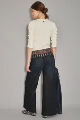 Jean de corte oxford y tiro alto, confeccionado en denim azul oscuro con un ligero lavado. Presenta un diseño de pierna ancha que se ensancha desde la cadera hacia el ruedo, con cierre y botón frontal.