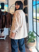 Campera de ecocuero color chocolate, con corte amplio y relajado. Presenta cuello camisero, cierre frontal con botones metálicos y bolsillos frontales de gran tamaño.