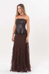 Pollera larga color chocolate confeccionada en microtul, totalmente forrada, con diseño fluido y volados en cascada que aportan movimiento.