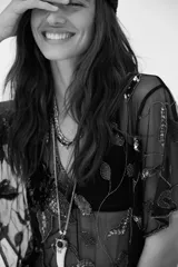 Collar largo de estilo boho con cadena metálica, cuentas de vidrio y dije central con forma de colmillo y piedra oscura.