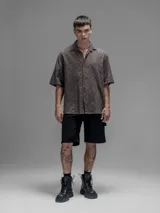 Camisa clásica de manga corta, color chocolate con efecto desgaste, confeccionada en algodón bordado (broderie) con diseño floral calado. Presenta cuello abierto y calce oversize.