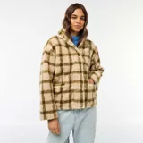 Chaqueta de tejido polar o efecto borreguito, color beige con estampado a cuadros en tono verde oliva. Presenta cuello alto con cierre de cremallera frontal.