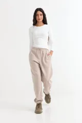 Pantalón jogger de felpa en color beige, con cintura elástica ajustable mediante cordón y puños elásticos en los tobillos.