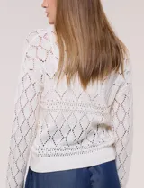 Cardigan de punto color beige con trama calada, escote en V pronunciado, cierre frontal con botones efecto carey y mangas largas.