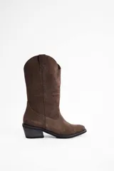Bota de caña media estilo western, confeccionada en cuero vacuno con acabado de gamuza en color marrón, con taco cuadrado y puntera redondeada.