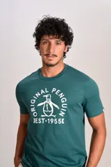 Remera de algodón color verde petróleo con cuello redondo y mangas cortas. Presenta un estampado gráfico frontal en color blanco con el logo de la marca y la leyenda Original Penguin Est. 1955.