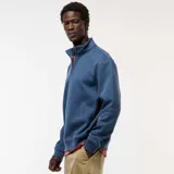 Buzo azul con cuello alto y cremallera parcial.