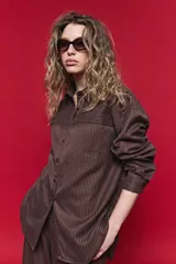 Camisa de manga larga con diseño de rayas verticales y horizontales en color marrón. Presenta un corte oversize con hombros caídos, cuello clásico y cierre frontal con botones.