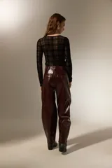 Pantalon de eco-cuero con diseño barrel, de tiro alto y corte holgado. Cuenta con bolsillos laterales y cierre frontal con botón.