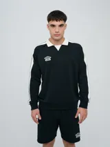 Buzo deportivo Umbro modelo Mixtape, color negro con cuello polo blanco y franjas blancas en las mangas con logo de la marca. Cuenta con puños y cintura elastizados.