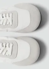 Sneaker Sofi de estilo minimalista en color gris claro, confeccionada en una combinación de piel vacuna y poliéster con detalles de gamuza en la puntera y el talón. Presenta cierre con cordones y un diseño fruncido en la parte trasera con elástico.
