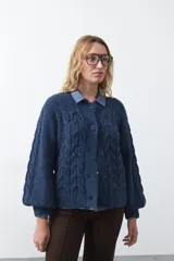 Cardigan de tejido de punto color marrón chocolate, con diseño de trenzas en el frente y mangas. Presenta cuello redondo, cierre frontal con botones al tono y puños acanalados.